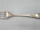 a close up of a fork on a table with a spoon on it