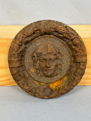 une plaque en bois sur laquelle est représenté un visage, à côté d'une autre plaque en bois