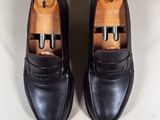 pair of black loafers with buckles on top of a white surface