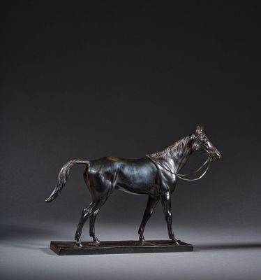 statue en bronze représentant un cheval posée sur un socle en bois, sur fond gris