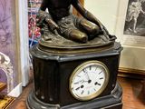 une statue d'un homme assis au sommet d'une horloge
