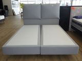 un lit sur lequel sont posés deux matelas, dans une chambre