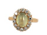 un gros plan d'une bague en or sertie d'une pierre verte entourée de diamants blancs