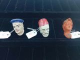 three ceramic heads of people are on display in a case