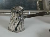 a silver tea pot with a wooden handle on a table