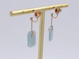 pair of gold and blue stone earrings on a gold plated stand