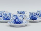 six blue and white cups and saucers on a white surface