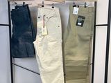 deux pantalons pour homme suspendus à un portant dans un magasin de vêtements