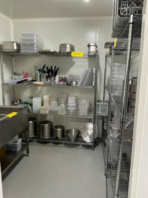 une cuisine avec beaucoup d'étagères sur lesquelles sont posées des casseroles et des poêles