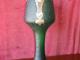 a green and gold vase on a wooden table