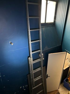 une échelle appuyée contre un mur bleu dans une pièce