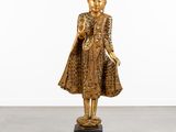 une statue en or représentant une femme en robe, debout sur un socle