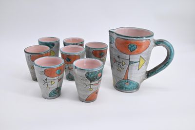 six cups and a pitcher on a white table