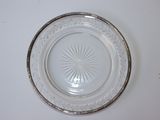 une assiette en verre bordée d'argent posée sur une table blanche