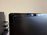 a black computer monitor sitting on a desk next to a laptop