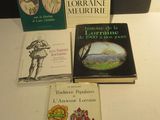 Plusieurs livres sont posés sur une table devant une lampe.