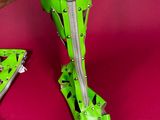 someone is holding a pair of green high heels with a zipper