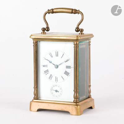 une petite horloge en laiton avec des chiffres romains sur le cadran