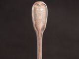 an old silver spoon with a heart shaped handle sitting on top of a table