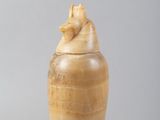 un vase en bois orné d'un oiseau, à côté de noix