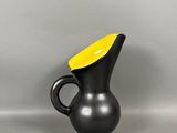 vase noir et jaune, avec un haut jaune sur un fond gris