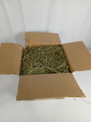 une boîte en carton remplie de foin posée sur une surface blanche