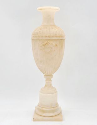 un vase ancien sculpté posé sur un socle, sur fond blanc