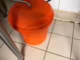 un seau orange posé à côté des toilettes dans une salle de bains