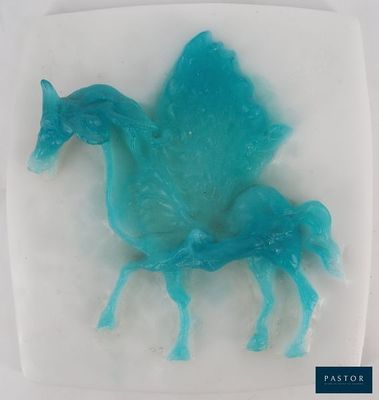 un cheval bleu posé sur une assiette blanche