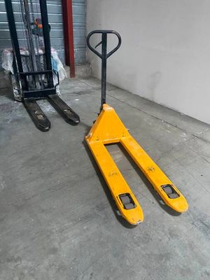 un chariot élévateur jaune garé à côté d'une pile de palettes