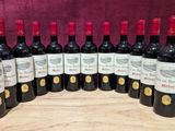six bottles of red wine are lined up on a wooden board