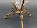 an antique glass vase on a stand on a gray surface
