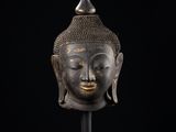 a bronze head of a buddha on a black background