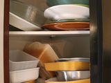 many bowls and pans in a cabinet together