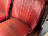 two red leather seats in the back of a car
