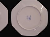 two white plates with blue designs on them on a black table