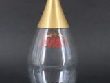 an empty glass bottle with a gold cap on a black background