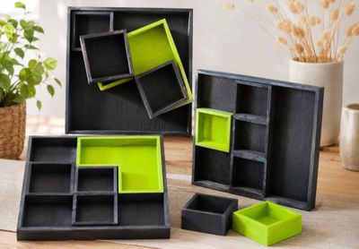 Trois boîtes noires et vertes sont posées sur une table, à côté d'une plante en pot.