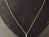 a gold necklace with a red stone on a black mannequin