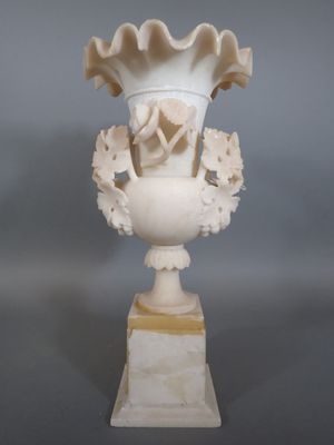 un vase blanc orné de fleurs, posé sur un socle
