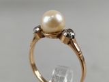 a close up of a ring with a pearl and diamonds on it