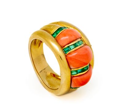 un gros plan d'une bague en or sertie de pierres orange et vertes