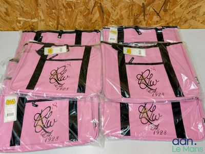 three bags of pink bags with black trims are on a table