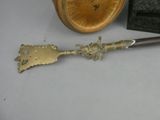 a small metal object with a wooden clock in the background