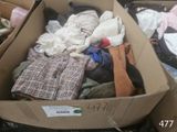 a cardboard box full of clothes that is sitting on the ground