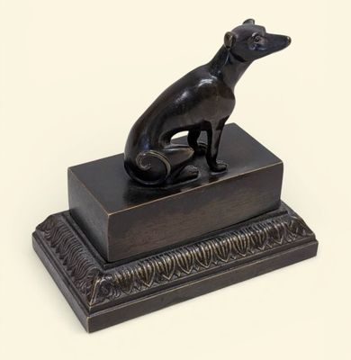 statue d'un chien assis sur une boîte posée sur une surface blanche