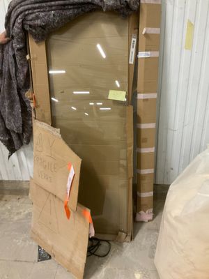 un homme debout à côté d'une pile de cartons et d'un grand miroir