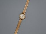une montre-bracelet en or avec un cadran blanc sur un fond gris