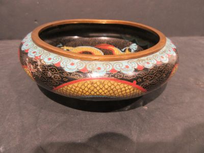 un bol noir orné d'un dragon, posé sur une table