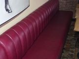 a red leather bench in a restaurant with a horse painting on the wall